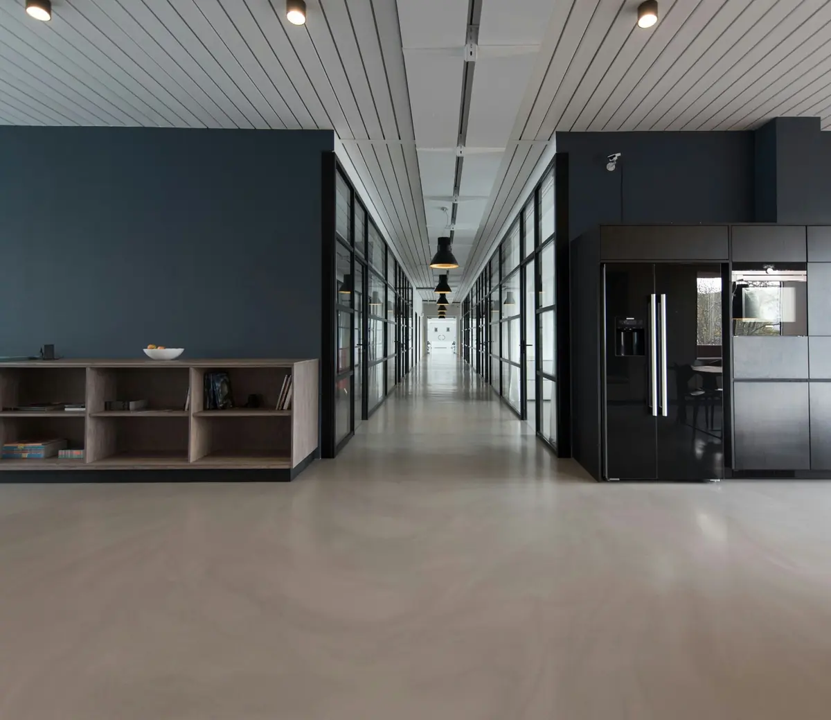 Lacivert duvarlı, cam bölmeli modern bir ofis koridoru
